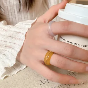 Close-up of stylish translucent irregular resin rings worn by a model holding a coffee cup