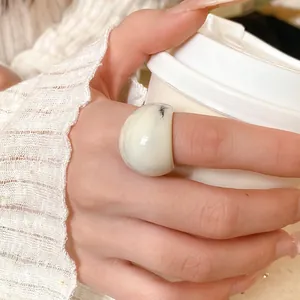 Macro view of an irregular marble resin ring worn on a finger for a stylish look.