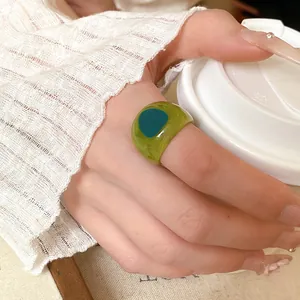 Close-up detail of a translucent green chunky resin ring with teal oval pattern on hand