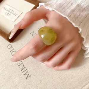 Unique irregular green marble resin ring worn on a stylish hand, artistic detail view.