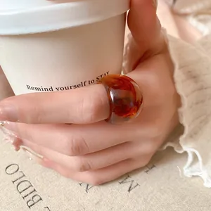 Close-up of a translucent chunky amber resin ring with marbled texture worn on a hand.