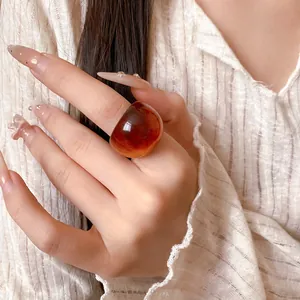 Macro view of an irregular resin ring featuring an amber swirl texture and transparent finish