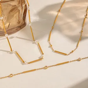 Detalle macro del collar dorado con forma de bambú, circonitas redondas y perlas blancas.