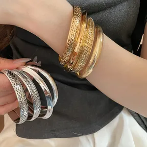 Detailed view of stackable gold and silver hollow-out metal bangles on wrist