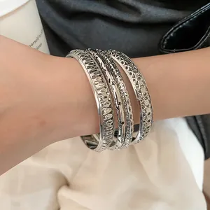 Macro view of textured silver hollow bangles set worn on a female wrist.