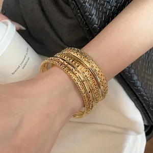 Detail view of golden hollow-out bangles with intricate metallic textures and patterns