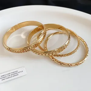Close-up detail showing intricate hollow-out patterns on gold-plated metal bangles