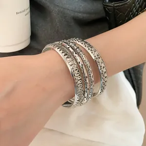 Detailed close-up view of layered silver hollow-out metal bangles with textured patterns