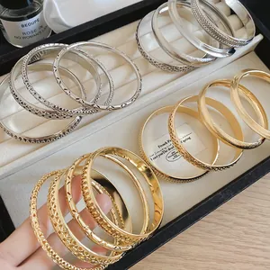 Close-up of gold and silver metallic bangles with hollowed-out and matte textures