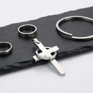 Primer plano de un colgante de cruz de acero inoxidable grabado con anillos y pulsera