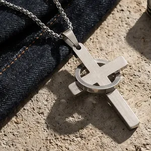 Primer plano de un colgante de cruz de acero inoxidable retro con grabado y anillo