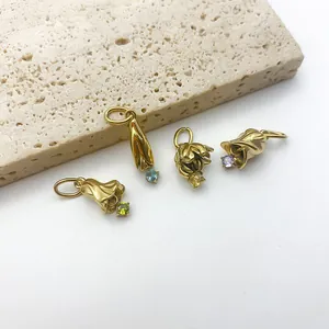 Détail de quatre pendentifs fleurs en acier titane doré avec pierres de naissance