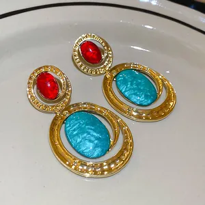 Dettaglio delle orecchini vintage in oro con pietre rosse e turchesi incastonate.