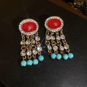 Dettaglio orecchini vintage con ovale rosso e catenelle con perline blu