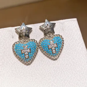 Primo piano dettagliato di orecchini vintage a cuore con perline blu e croce