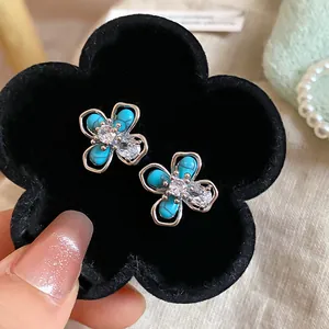 Dettaglio di orecchini a fiore turchesi con cristalli in un vassoio di velluto nero