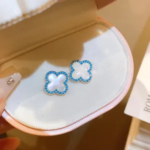 Primo piano di orecchini a quadrifoglio vintage con madreperla bianca e bordo blu