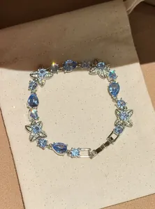 Detailed macro view of an elegant blue crystal flower bracelet displayed on a beige fabric pouch