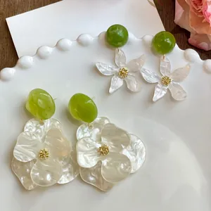 Detailed view of white gardenia flower earrings with green resin accents.