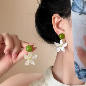 Elegant white gardenia flower drop earrings with green beads shown on an Asian model.