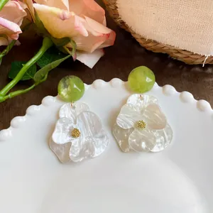 Detailed view of white gardenia flower earrings with green marble bead