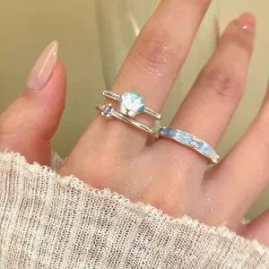 Close-up of blue shell and gradient enamel rings worn with a soft white knitted sleeve.