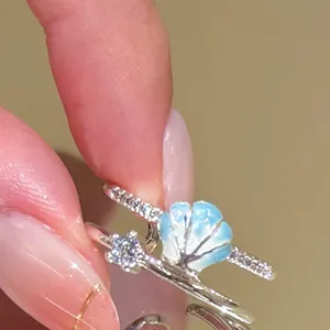 Macro detail of a silver adjustable ring featuring a blue enamel shell and a sparkling star