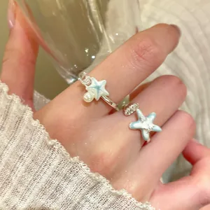 Close-up of blue starfish and shell adjustable rings worn for summer vacation style.