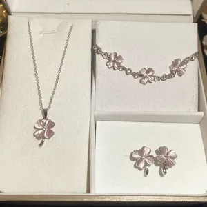 Detailopname van een elegante roze kattenoogsteen klavertje vier sieradenset in doos
