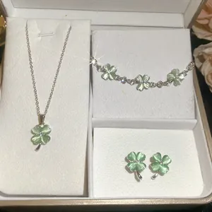 Detailopname van een luxe groene kattenoog steen klaver sieradenset in een wit geschenkdoos