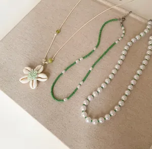 Set aus drei Sommerketten mit Muschelblumenanhänger, grünen Perlen und weißen Perlen.