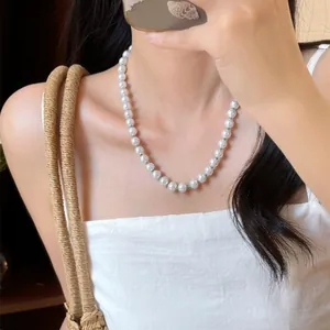 Elegante weiße Perlenkette mit grünen Perlen am Hals für einen frischen Sommerlook