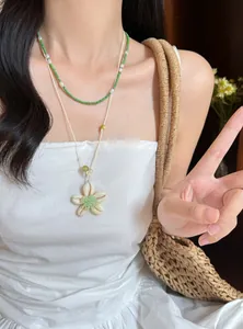 Detailansicht von grünen Perlen- und Muschelblumenketten im Lagenlook am Model