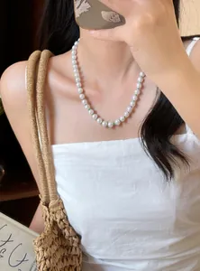 Elegante Halskette mit weißen Perlen und grünen Akzenten an einem Modell für den Sommer