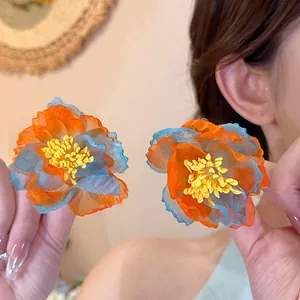 Detailed view of oversized holiday style chiffon flower stud earrings in orange and blue