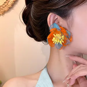 Close-up of vibrant orange and blue chiffon flower earring on model