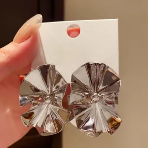 Detailed view of silver-toned vintage earrings with abstract folded metal design.