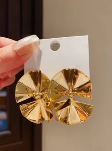 Close-up of sculptural gold fan-shaped earrings with glossy metallic finish