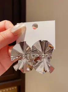 Close-up of abstract silver pleated fan-shaped stud earrings with metallic luster