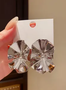 Detailed close-up of metallic silver fan-shaped stud earrings with reflective pleated finish