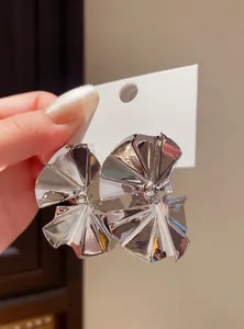 Macro shot of shiny silver pleated fan-shaped stud earrings showing metal texture