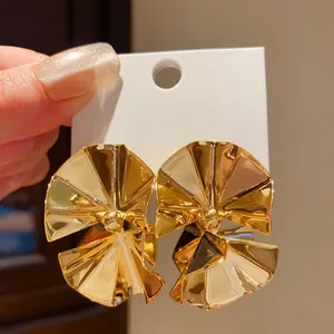 Macro view of gold fan-shaped geometric earrings with high-shine metallic finish