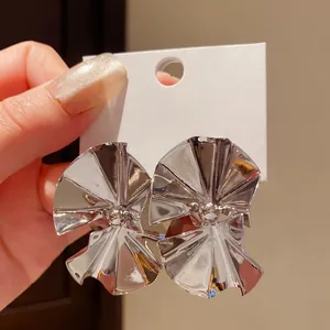 Close-up of retro silver-toned pleated fan-shaped stud earrings on a white display card