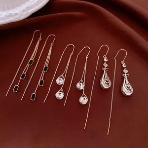 Detailed view of three 14K gold-plated crystal teardrop and musical lute ear threads.
