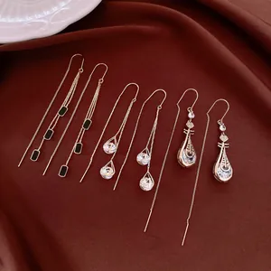 Selection of 14k gold plated long tassel earrings with crystals on brown fabric background