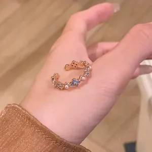Close-up detail of a French vintage gold ring featuring blue flowers and pearls held in hand