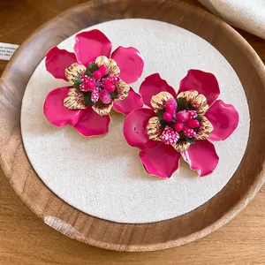 Detailed macro view of vibrant pink oil-dripped flower earrings with gold accents.