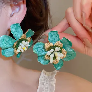 Exquisite close-up view of vintage green enamel flower earrings with textured gold accents