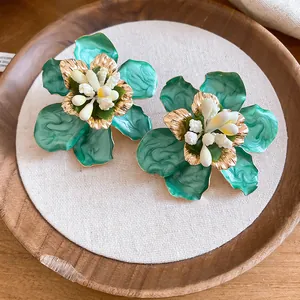 Close-up detail of vintage green enamel flower stud earrings with gold accents and white stamens