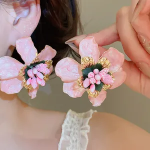 Detail shot of vintage pink floral earrings with textured petals and gold centers